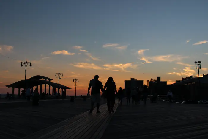 A photo of two people walking at sunset at Coney Island